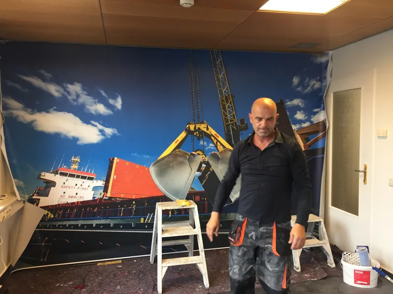 Behanger staat voor een net geplaatst fotobehang met een havenkraan en een schip