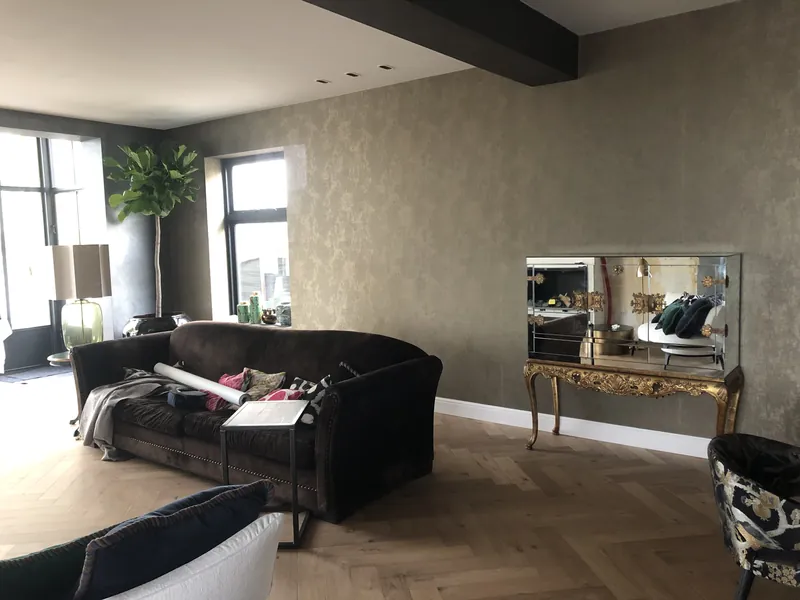 Woonkamer met een wand van structuurbehang in grijsgroen met goud